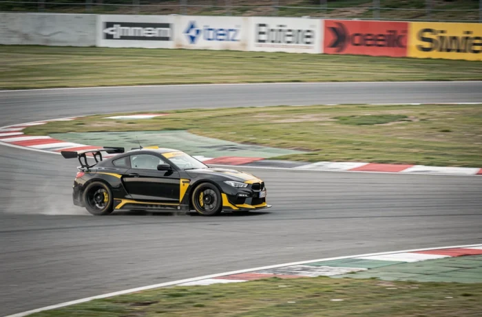 Voiture de sport noire et jaune en pleine accélération dans un virage lors d'un stage de pilotage sur circuit
